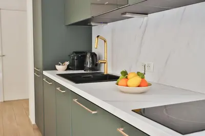 a kitchen with green cabinets and a couch at Spacieux T2 avec grande terrasse à 200m de la plage in Cannes