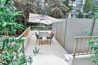 a patio with a table and chairs and an umbrella at Spacieux T2 avec grande terrasse à 200m de la plage in Cannes