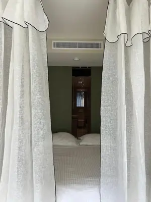 a bed with white curtains in a bedroom at Palm Beach front de mer in Cannes