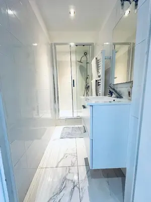 a white bathroom with a sink and a mirror at Grand appartement centre piéton Cannes in Cannes
