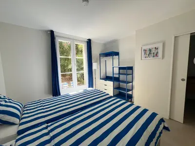 a bedroom with a blue and white striped bed and a window at Splendide maison Solstice in Cannes