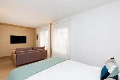 a bedroom with a bed and a couch and a television at Côté Croisette LUXE - 2BdR 2 bthR 2 toilets -Terrace, AC, parking & lift in Cannes