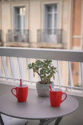 two red cups and a potted plant on a table on a balcony at FRGK Victoria 4 Central Cannes 1BR Terrace, AC & Ultra-Fast Wi-Fi in Cannes
