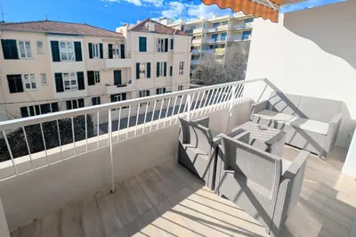 a balcony with two chairs and a railing with buildings at 