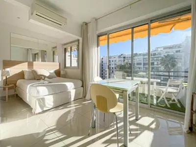 a bedroom with a bed and a table and a balcony at Le ROUAZE studio - proche Carlton et Martinez - idéal congrès - Wifi Clim in Cannes