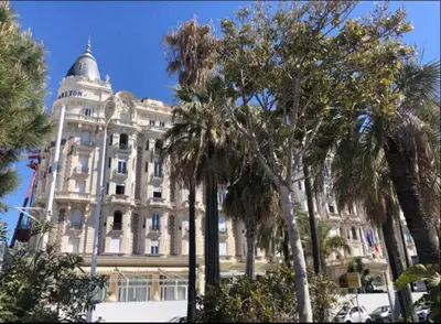 a large building with palm trees in front of it at Le ROUAZE studio - proche Carlton et Martinez - idéal congrès - Wifi Clim in Cannes