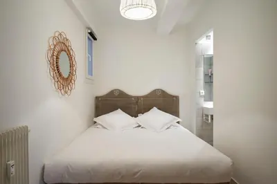 a bedroom with a bed with white sheets and a mirror at Cannes Center, Nice 110m2, 3BR & 3BTH, Terrace in Cannes