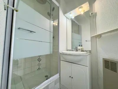 a white bathroom with a sink and a shower at Vogue By SCLS Locations in Cannes