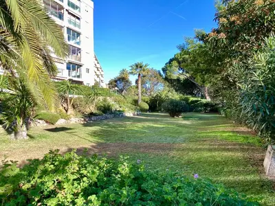 a park with palm trees and a building at Vogue By SCLS Locations in Cannes