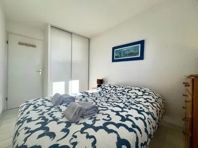 a bedroom with a bed with a blue and white comforter at Vogue By SCLS Locations in Cannes