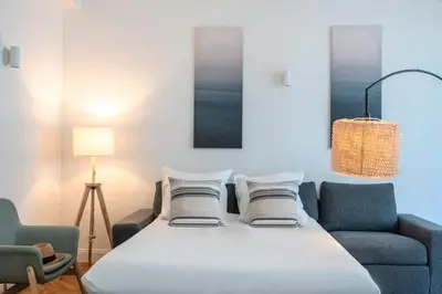 a bed in a room with two chairs and a lamp at Le Palais Madrid in Cannes