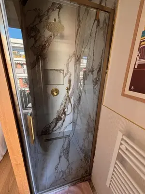 a glass shower door with a marble wall at Superbe appartement Art Déco avec roof top in Cannes