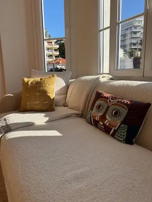 a couch with pillows in a room with a window at Superbe appartement Art Déco avec roof top in Cannes