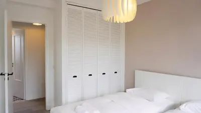 a white bedroom with a bed and a chandelier at Proche Croisette, Appartement 2 Chambres by Palmazur Vacances in Cannes