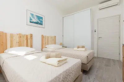 two beds in a bedroom with white walls and wood floors at Modern Jaurès-Center-Clim-Wifi-Festival in Cannes