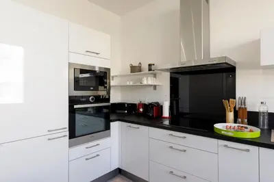 a kitchen with white cabinets and black appliances at Modern Jaurès-Center-Clim-Wifi-Festival in Cannes