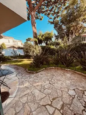 a stone walkway with a tree in a yard at Agréable 2 pièces avec terrasse et jardin in Cannes