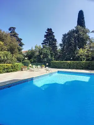 a large blue swimming pool with chairs and trees at Superbe studio jardin, terrasse, piscine 307L Kali in Cannes