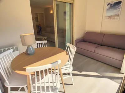 a living room with a table and chairs and a couch at Superbe studio jardin, terrasse, piscine 307L Kali in Cannes