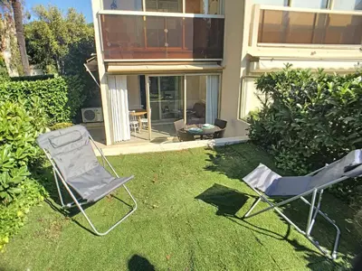 two lawn chairs sitting in the grass in front of a house at Superbe studio jardin, terrasse, piscine 307L Kali in Cannes