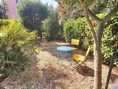 a blue table and two chairs in a garden at Superbe studio jardin, terrasse, piscine 307L Kali in Cannes