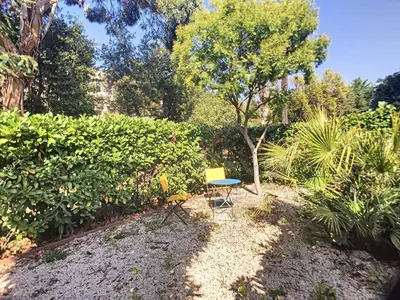 a chair and a table in a garden at Superbe studio jardin, terrasse, piscine 307L Kali in Cannes