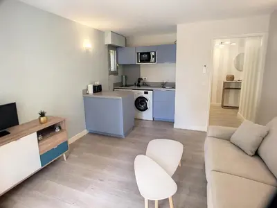 a living room with a couch and a kitchen at Superbe studio jardin, terrasse, piscine 307L Kali in Cannes