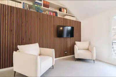 a living room with a chair and a tv on a wall at 3 bedrooms 2 terraces in Cannes in Cannes