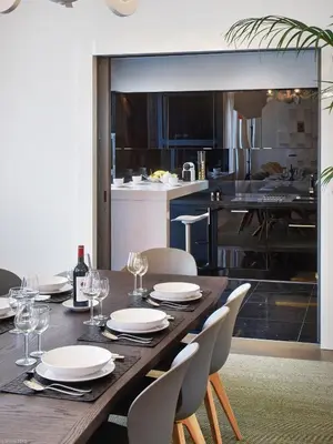 a wooden table with plates and wine glasses and a kitchen at Arthur Properties Croisette in Cannes