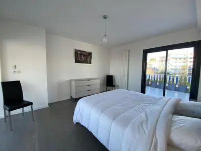 a white bedroom with a large bed and a chair at C010 - Magnifique Appartement Toit Terrasse in Cannes