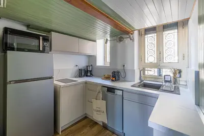 a small kitchen with white cabinets and a refrigerator at L'HONORAT vue mer et port, à côté des plages du Midi et proche du Palais in Cannes