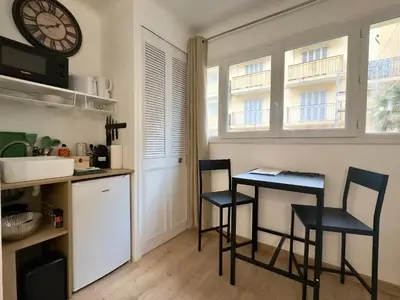 a kitchen with two chairs and a table and a clock at Haute-Rive By SCLS Locations in Cannes