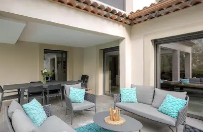 a patio with couches and a table and chairs at Villa Spacieuse - Piscine chauffée - Climatisé in Mougins