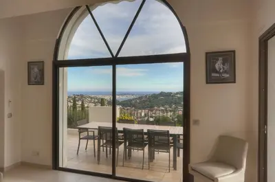a dining room with a table and chairs and a large window at IMMOGROOM - Exceptional Villa - Sea View - Pool in Vallauris