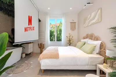 a bedroom with a white bed and a television at La Suite Jardin Secret in Cannes