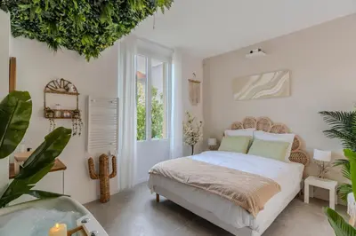 a bedroom with a bed and a large window at La Suite Jardin Secret in Cannes