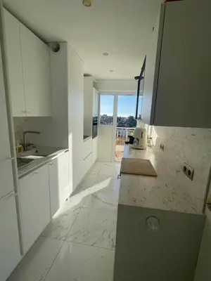 a kitchen with white cabinets and a view of the ocean at appartement centre ville cannes vue mer in Cannes