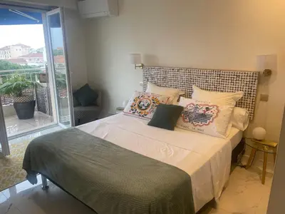 a bedroom with a bed with pillows and a balcony at appartement centre ville cannes vue mer in Cannes