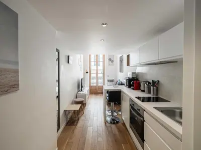 a kitchen with white cabinets and a wooden floor at Bright duplex-Cannes Centre -Mobility lease in Cannes