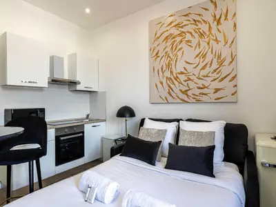 a small bedroom with a bed and a kitchen at Sublime studio - Cannes center - Mobility lease in Cannes