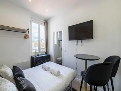 a room with a bed and a table and a tv at Sublime studio - Cannes center - Mobility lease in Cannes