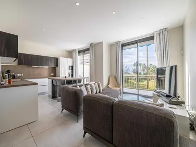 a living room with a couch and a tv and a kitchen at Appt Exclusif - 4BR 8P- Parking - Croisette in Cannes