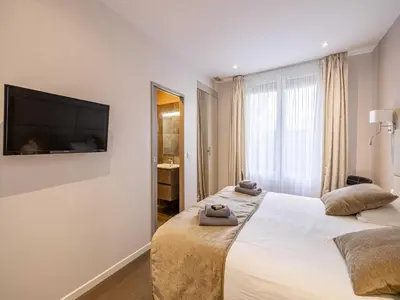 a bedroom with two beds and a flat screen tv at Appt Exclusif - 4BR 8P- Parking - Croisette in Cannes