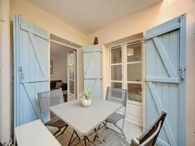 a table and chairs in a room with blue doors at Cosy flat in Cannes - Mobility lease in Cannes