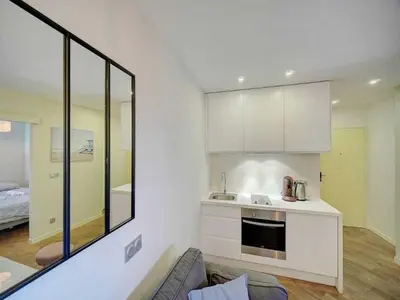 a kitchen with white cabinets and a couch in a room at Cosy flat in Cannes - Mobility lease in Cannes