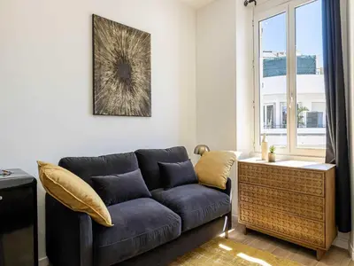 a living room with a blue couch and a window at Magnificent studio Cannes center - Mobility lease in Cannes