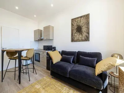 a living room with a blue couch and a kitchen at Magnificent studio Cannes center - Mobility lease in Cannes