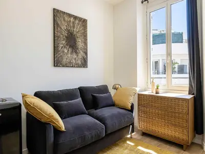 a living room with a blue couch and a window at Magnificent studio Cannes center - Mobility lease in Cannes