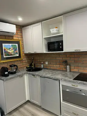 a kitchen with white cabinets and a brick wall at Studio - Suquet Forville in Cannes