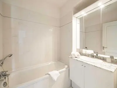 a white bathroom with a tub and a sink at Charming apt with balcony pool - 1BD 2P - Cannes in Cannes